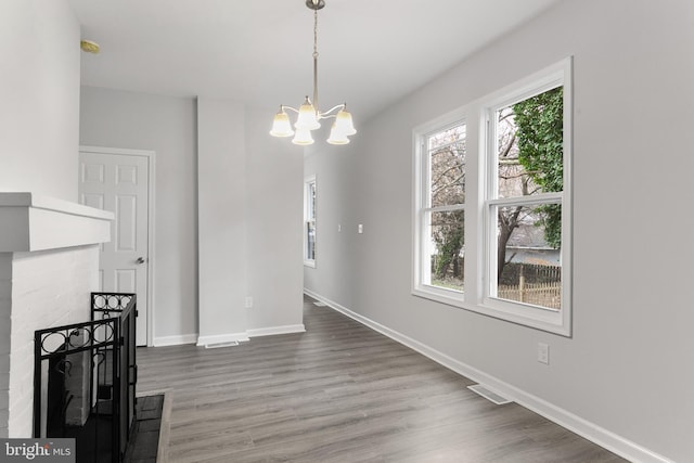 unfurnished dining area featuring a wealth of natural light, hardwood / wood-style floors, and a chandelier