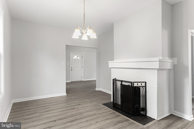 unfurnished living room with an inviting chandelier, a fireplace, and hardwood / wood-style flooring