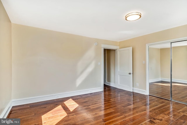 unfurnished bedroom with a closet and dark wood-type flooring