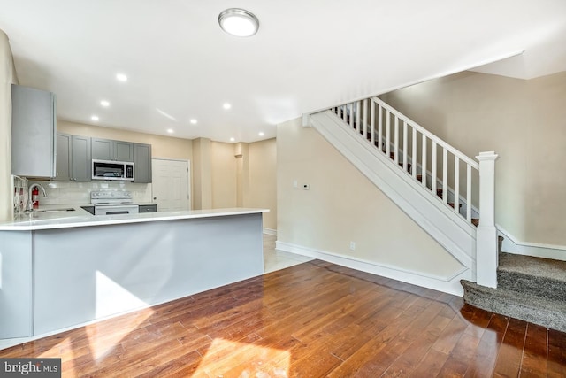 kitchen with kitchen peninsula, hardwood / wood-style floors, white range with electric cooktop, and gray cabinetry