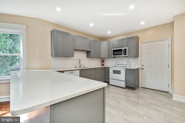 kitchen featuring white appliances, tasteful backsplash, gray cabinetry, and sink