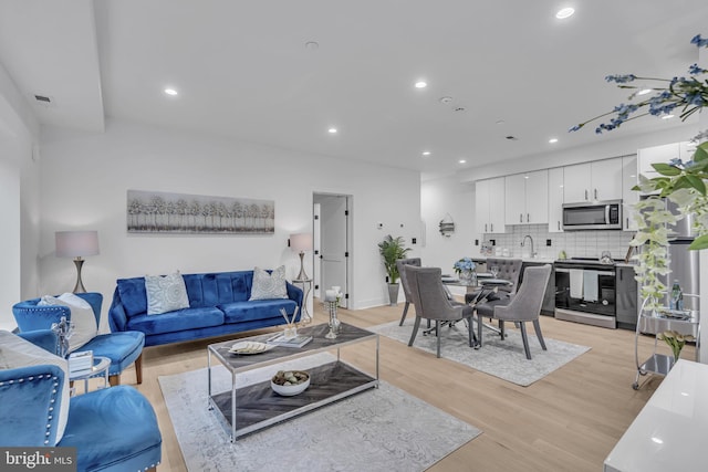 living room with light hardwood / wood-style flooring and sink