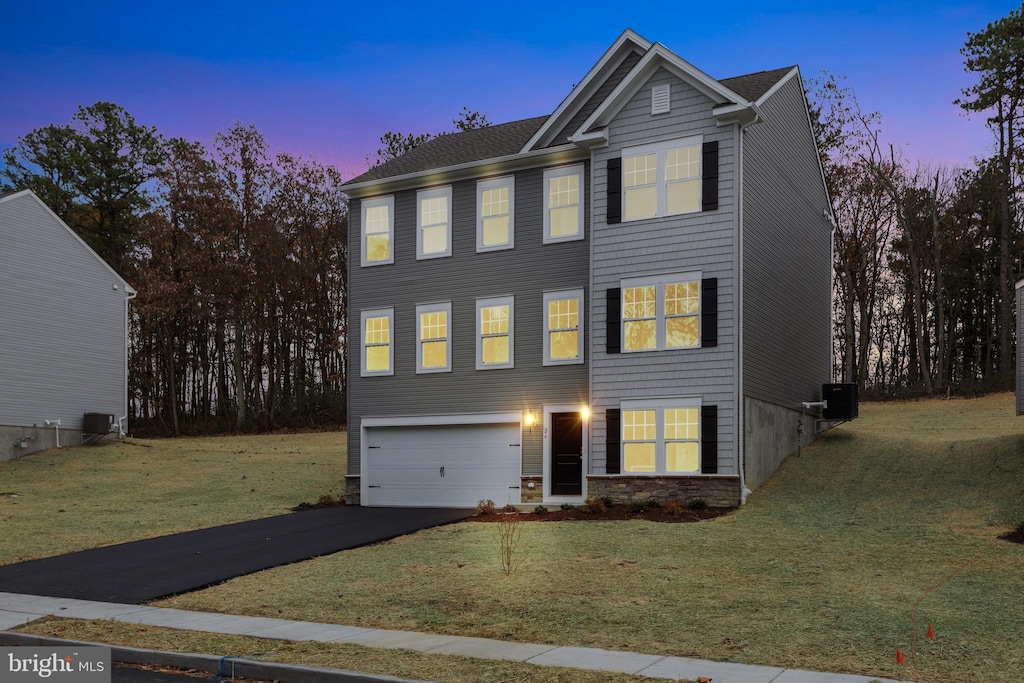 view of front of property with a garage, a lawn, and central air condition unit