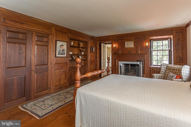 bedroom with dark hardwood / wood-style floors and wooden walls