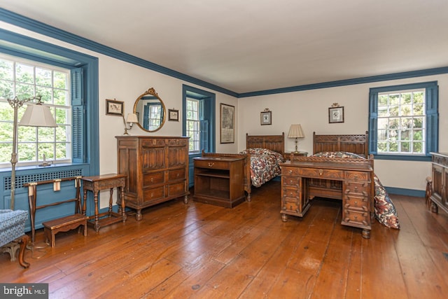 bedroom with ornamental molding, wood-type flooring, and radiator