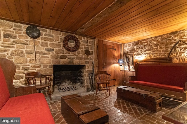 living area with wooden walls, a fireplace, and wood ceiling