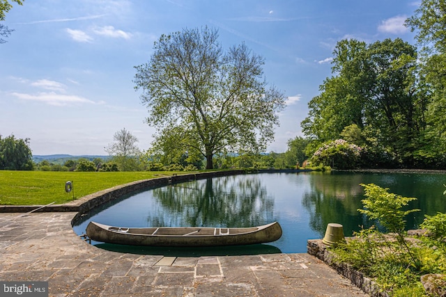 view of swimming pool featuring a water view and a yard