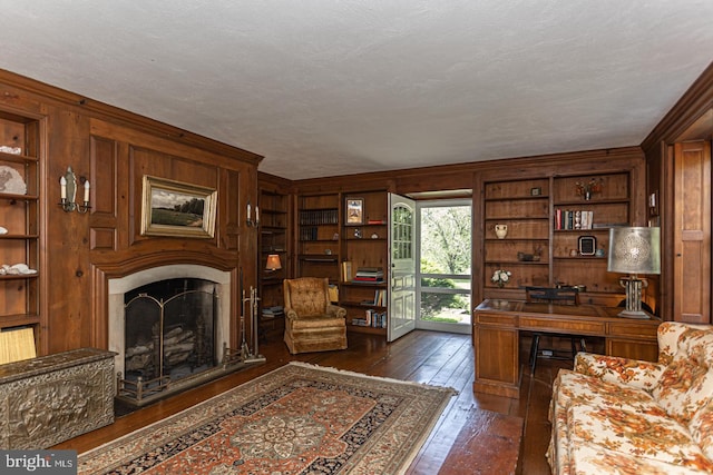 home office with a textured ceiling, wood walls, dark hardwood / wood-style flooring, and crown molding