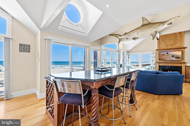 dining area featuring vaulted ceiling, light hardwood / wood-style flooring, and a water view