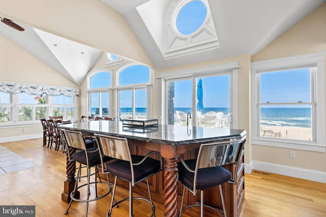 dining space featuring light hardwood / wood-style floors, lofted ceiling, and a water view