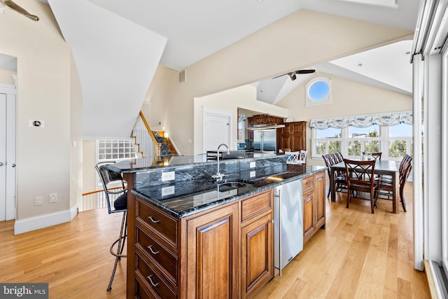 kitchen featuring a kitchen bar, dark stone counters, light hardwood / wood-style floors, and a center island