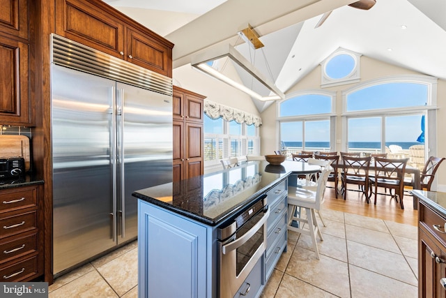 kitchen featuring a center island, dark stone countertops, light tile floors, and stainless steel appliances