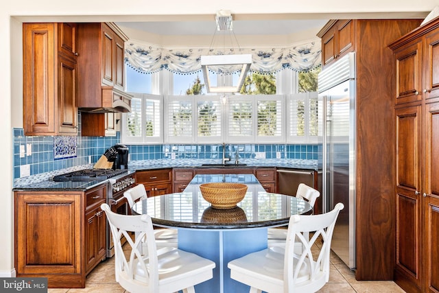 kitchen with a center island, dark stone countertops, premium appliances, tasteful backsplash, and light tile flooring