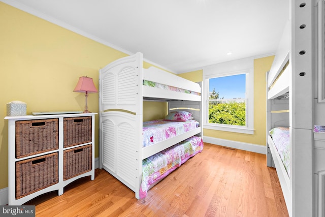 bedroom with ornamental molding and light wood-type flooring