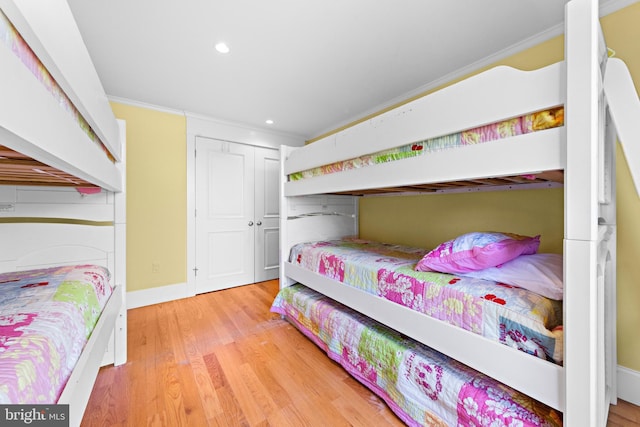 bedroom with a closet, light hardwood / wood-style floors, and ornamental molding