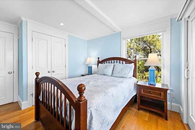 bedroom with a closet, light hardwood / wood-style flooring, and ornamental molding