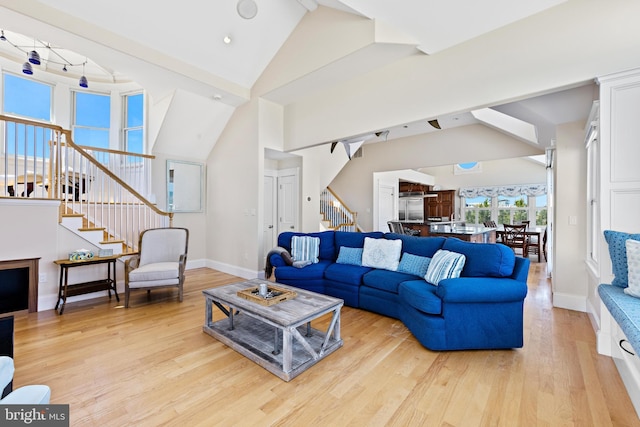 living room featuring high vaulted ceiling, light hardwood / wood-style flooring, and beamed ceiling