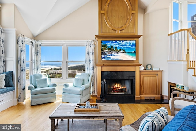 living room featuring high vaulted ceiling, a water view, and wood-type flooring