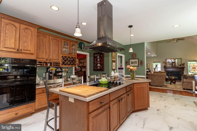 kitchen featuring black appliances, ceiling fan, decorative light fixtures, a kitchen island, and island exhaust hood