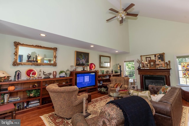 living room with ceiling fan, a towering ceiling, and hardwood / wood-style flooring