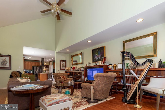 living room with wood-type flooring, ceiling fan, and a high ceiling