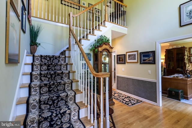 staircase with a towering ceiling and wood-type flooring