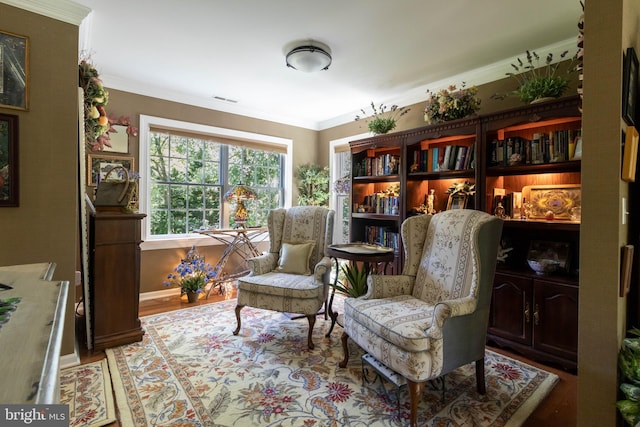 living area featuring wood-type flooring and ornamental molding