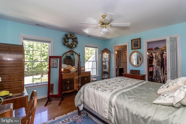 bedroom with multiple windows, ceiling fan, a closet, and hardwood / wood-style flooring