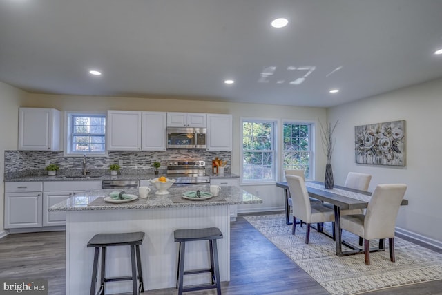 kitchen with stainless steel appliances, white cabinets, hardwood / wood-style floors, and a healthy amount of sunlight