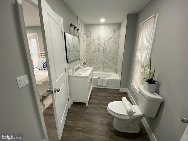 full bathroom featuring hardwood / wood-style flooring, tiled shower / bath combo, toilet, and vanity