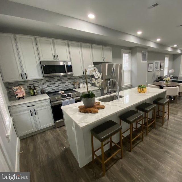 kitchen featuring sink, stainless steel appliances, dark hardwood / wood-style floors, a breakfast bar area, and a center island with sink