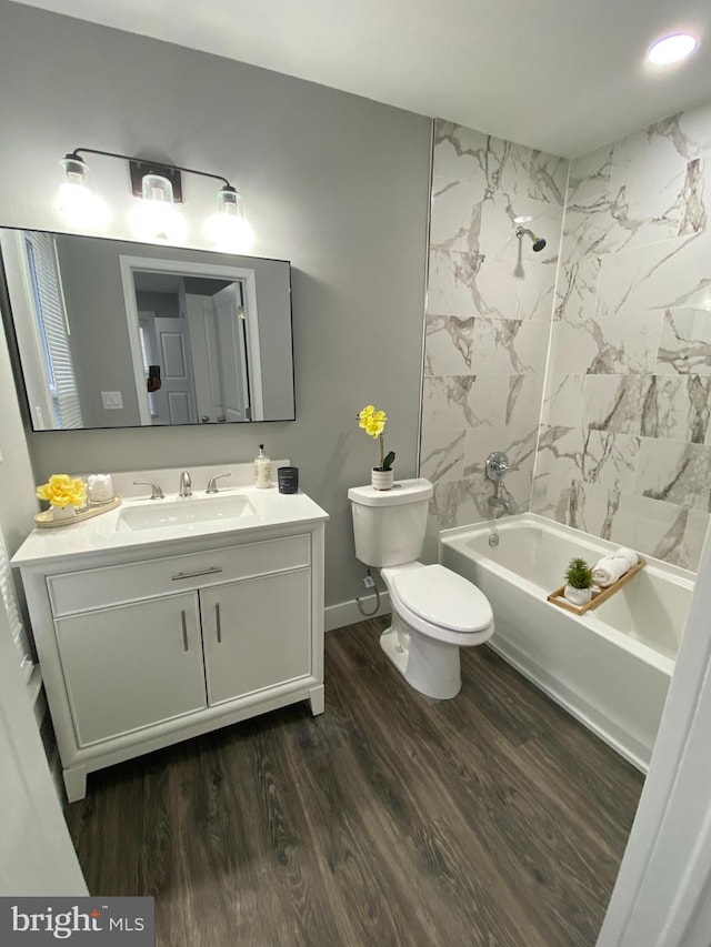 full bathroom featuring hardwood / wood-style floors, vanity, tiled shower / bath combo, and toilet