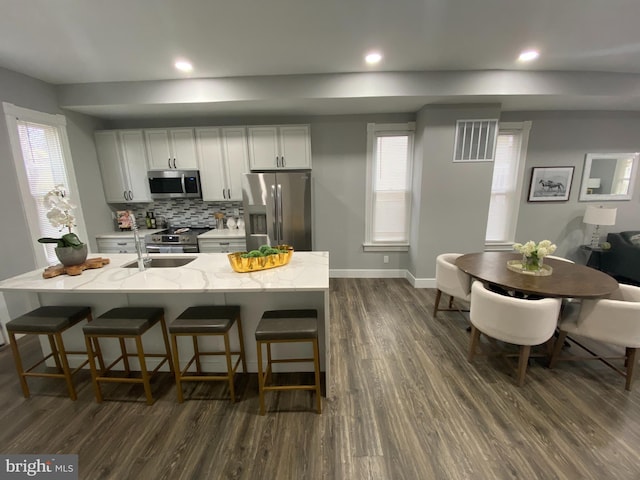 kitchen with light stone countertops, plenty of natural light, dark hardwood / wood-style floors, and appliances with stainless steel finishes