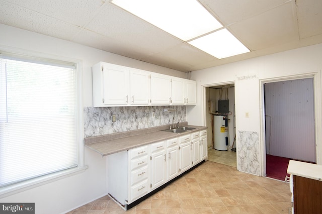 kitchen with white cabinets, a drop ceiling, sink, and water heater