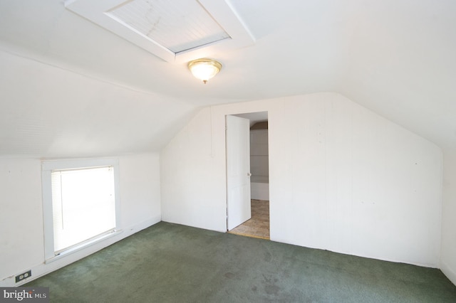 bonus room with dark colored carpet and vaulted ceiling