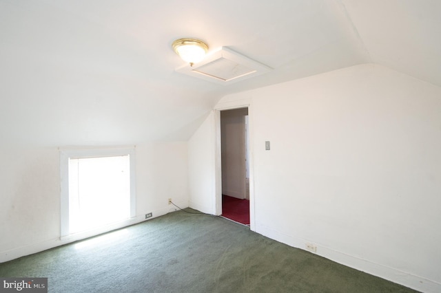 bonus room with dark colored carpet and vaulted ceiling