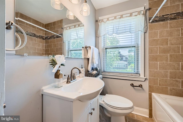 full bathroom with tile floors, tiled shower / bath, vanity, and toilet