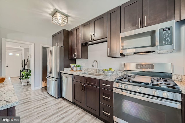 kitchen with appliances with stainless steel finishes, light hardwood / wood-style floors, sink, and dark brown cabinets