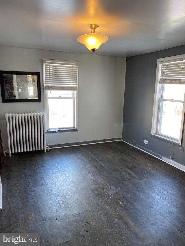 spare room with radiator heating unit and dark hardwood / wood-style flooring