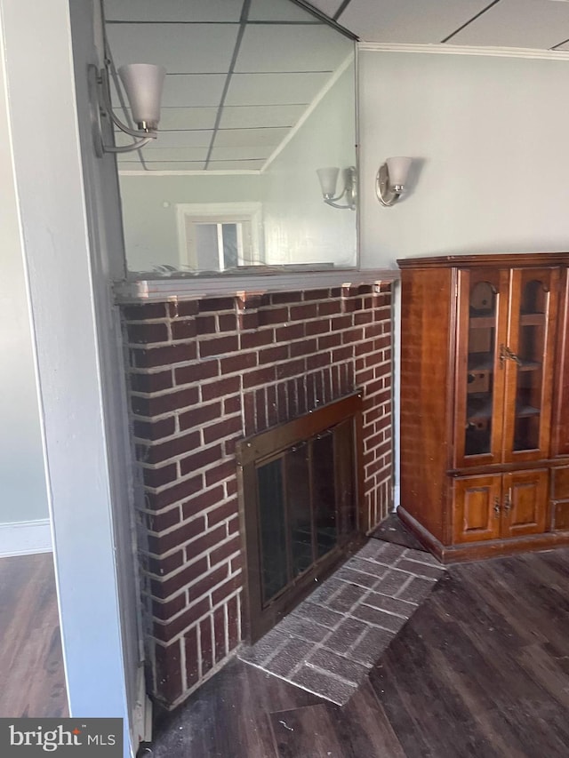 interior details featuring wood-type flooring, a brick fireplace, and a paneled ceiling