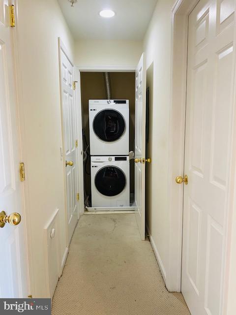 laundry area with stacked washing maching and dryer and light colored carpet