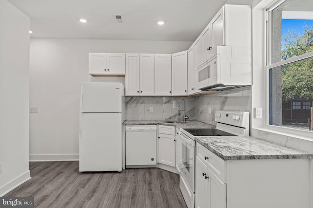 kitchen with white cabinetry, white appliances, light stone counters, hardwood / wood-style floors, and sink