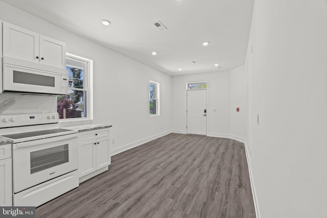 kitchen with white appliances, white cabinetry, and hardwood / wood-style floors