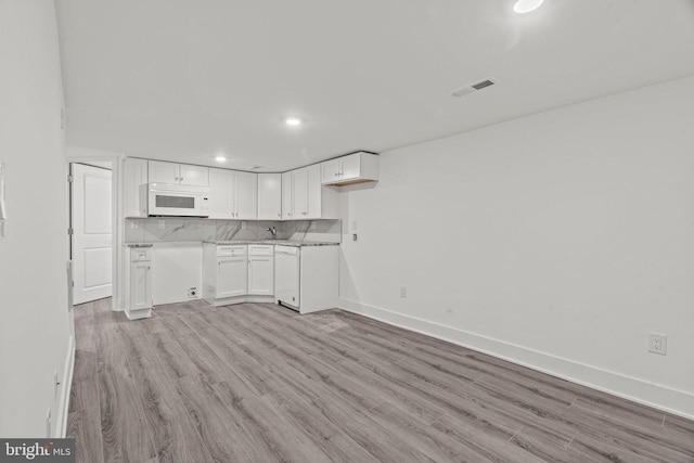 kitchen with white cabinets, light hardwood / wood-style floors, white appliances, and tasteful backsplash