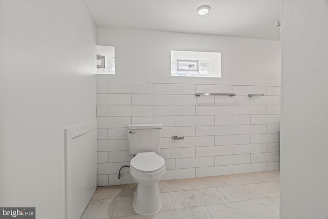 bathroom with tile walls, toilet, and tile floors