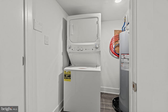 laundry room featuring stacked washer / dryer, dark hardwood / wood-style flooring, and water heater