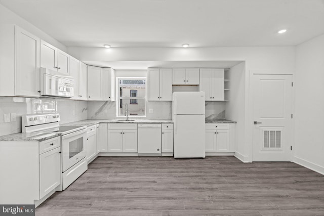 kitchen featuring light hardwood / wood-style floors, white appliances, backsplash, sink, and white cabinetry