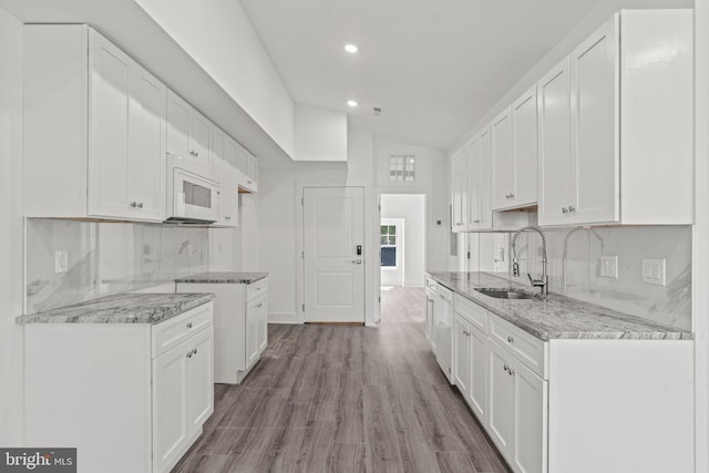 kitchen featuring white cabinets, vaulted ceiling, backsplash, hardwood / wood-style floors, and sink