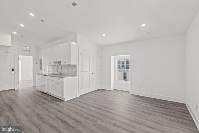 kitchen with wood-type flooring, white cabinetry, tasteful backsplash, and vaulted ceiling