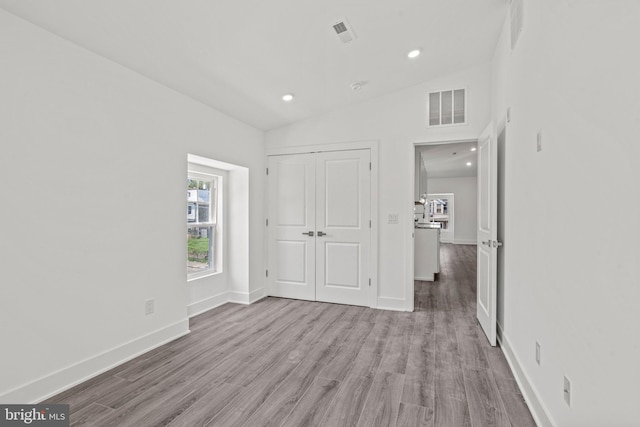 unfurnished bedroom with vaulted ceiling, hardwood / wood-style floors, and a closet